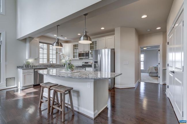 Bright and cheery kitchen features modern pendant lighting, granite countertops, and stainless steel appliances. | Image 7