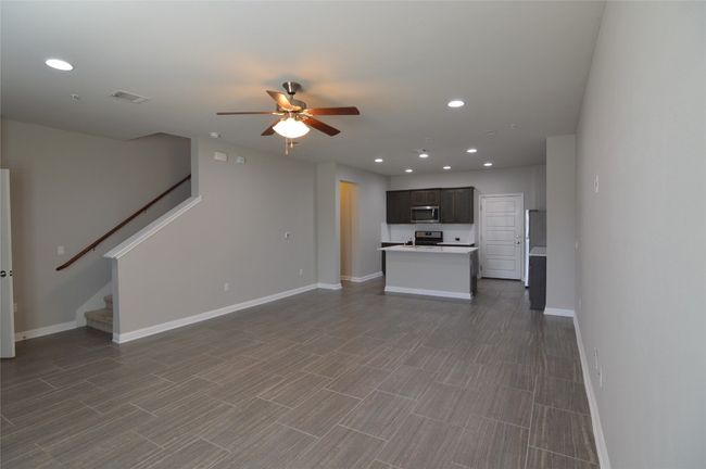 Unfurnished living room featuring a ceiling fan, stairs, baseboards, recessed lighting | Image 7