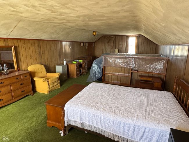 carpeted bedroom featuring a textured ceiling, vaulted ceiling, and wooden walls | Image 25