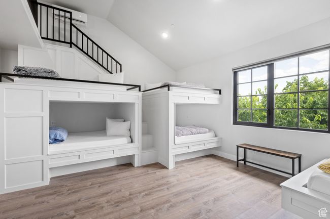 Unfurnished bedroom with lofted ceiling, light hardwood / wood-style floors, and an AC wall unit | Image 23