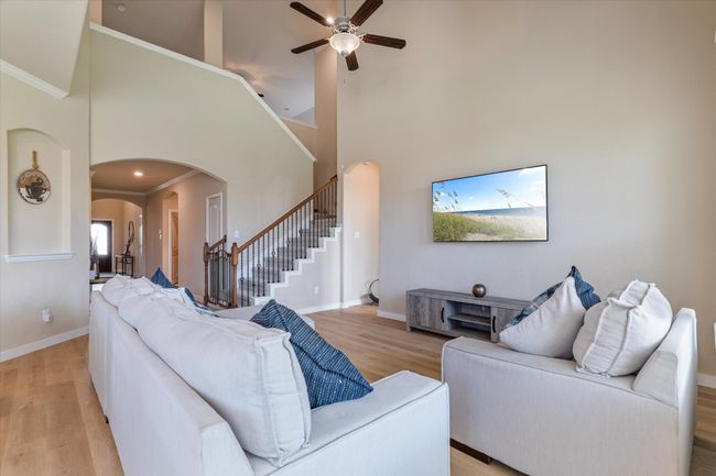 Living area featuring arched walkways, light wood-type flooring, a ceiling fan, stairs, and high vaulted ceiling | Image 9