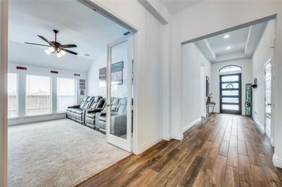 The modern design begins with the contemporary style front door with five glass panels and a transom window above. Durable wood-look tile flooring welcomes guests in the entry foyer, and a raised boxed ceiling with recessed lights adds architectural interest. | Image 3