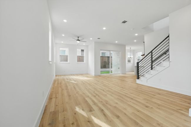 Unfurnished living room with light wood finished floors, recessed lighting, stairway, ceiling fan, and baseboards | Image 11