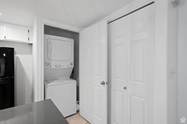 Washroom featuring laundry area, light tile patterned flooring, and stacked washing maching and dryer | Image 12