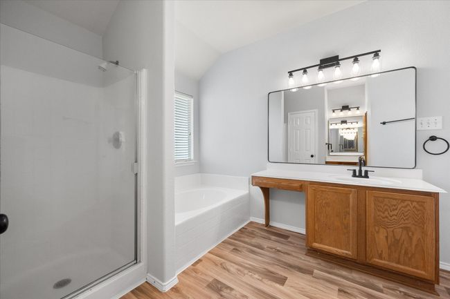 Bathroom with a bath, a shower stall, vanity, new laminate floors, and lofted ceiling | Image 25