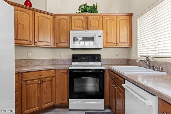 Kitchen with white appliances, light countertops, and brown cabinets | Image 13
