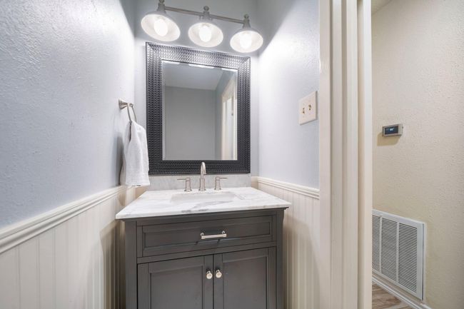 The updated half bath features a marble-topped vanity, brushed nickel fixtures, and modern lighting. | Image 18