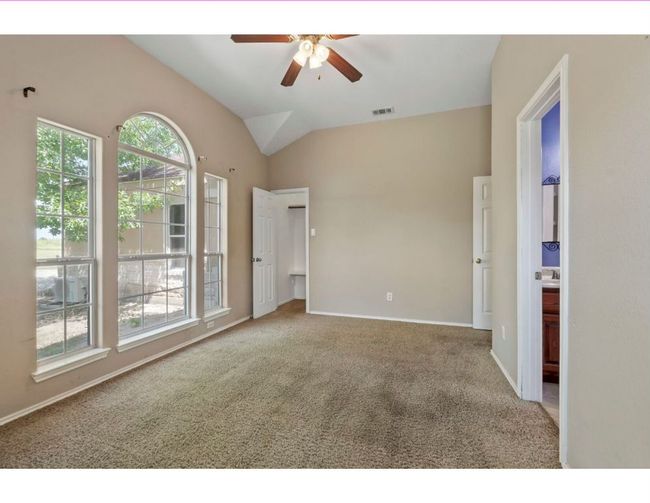 Unfurnished bedroom featuring carpet, lofted ceiling, ceiling fan, and ensuite bathroom | Image 25