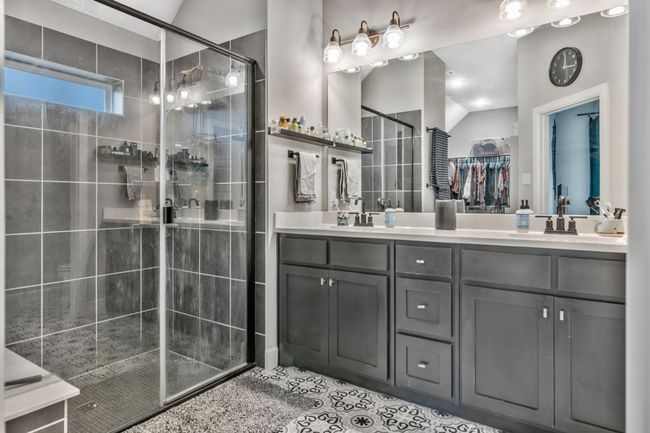 Bathroom featuring a shower stall, double vanity, lofted ceiling, a walk in closet, and tile patterned flooring | Image 17