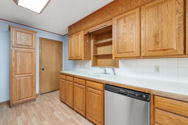Kitchen with dishwasher, backsplash, light countertops, and ornamental molding | Image 16