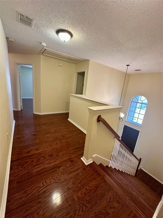 Corridor with an upstairs landing, a textured ceiling, attic access, and wood finished floors | Image 17