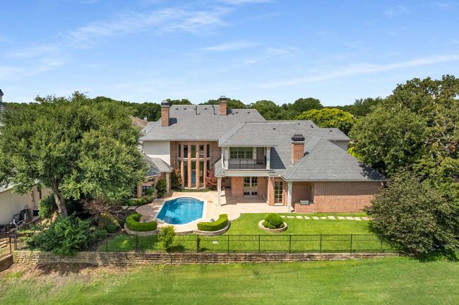 Rear view of property featuring a fenced backyard, a patio, a balcony, a chimney, and brick siding | Image 39