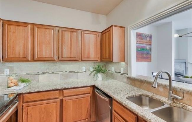 Kitchen with dishwasher, light stone counters, backsplash, and brown cabinets | Image 4