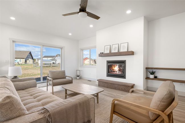 Living area featuring wood finished floors, a glass covered fireplace, recessed lighting, and ceiling fan | Image 18