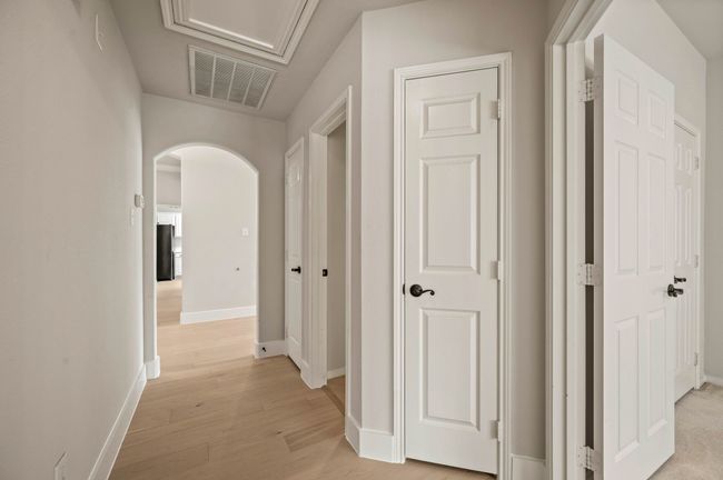 Hall featuring arched walkways, baseboards, light wood finished floors, and visible vents | Image 27