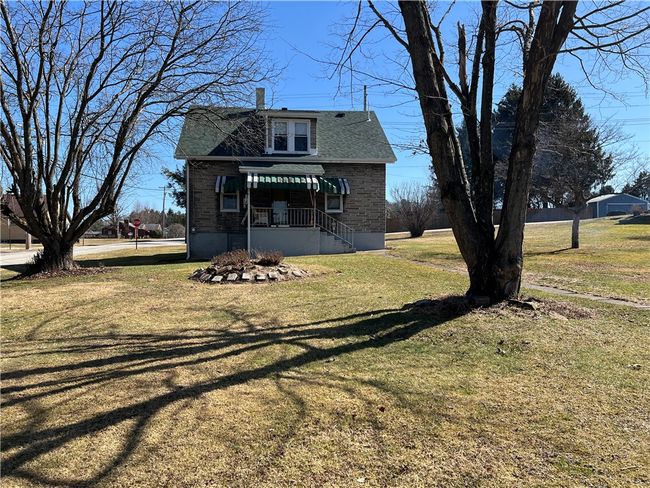 Back view of home with covered back deck. Walkway leads to detached garage. | Image 16