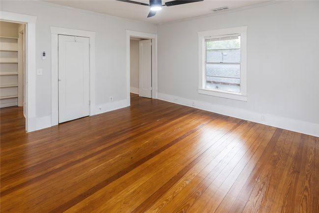 Unfurnished bedroom featuring wood-type flooring, ornamental molding, baseboards, a closet, and a ceiling fan | Image 19