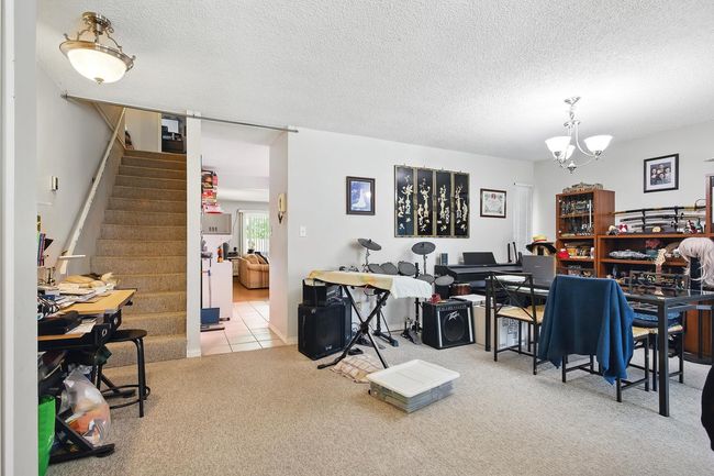 Carpeted office featuring a chandelier and a textured ceiling | Image 13
