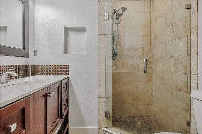 Bathroom featuring vanity, a shower stall, toilet, and decorative backsplash | Image 10