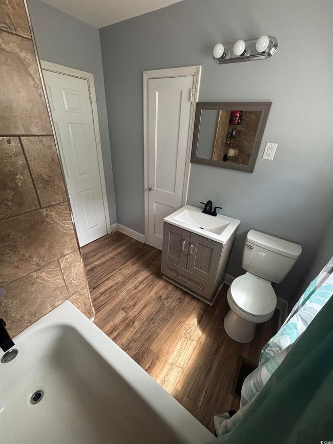 Bathroom featuring toilet, a bathtub, vanity, wood finished floors, and baseboards | Image 16