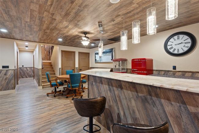 Bar featuring wood ceiling, stairway, wood finished floors, a bar, and pendant lighting | Image 48