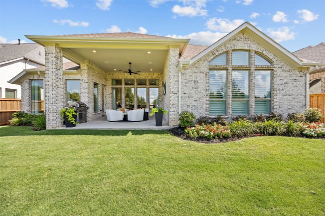 Back of property featuring a ceiling fan, brick siding, a patio area, and an outdoor living space | Image 35