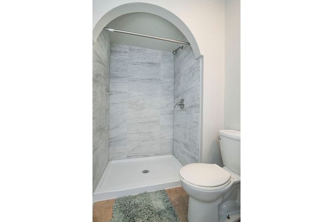 Bathroom with tile flooring, a tile shower, and toilet | Image 17