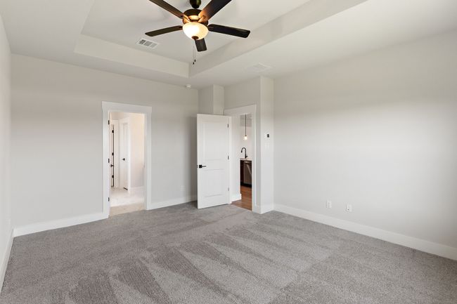 Unfurnished bedroom featuring carpet, a tray ceiling, and ceiling fan | Image 12