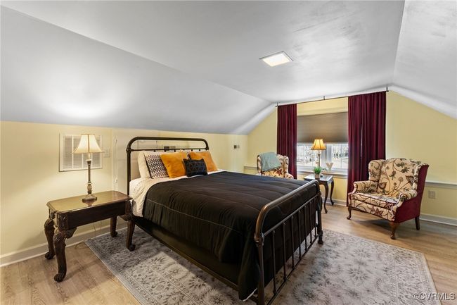Bedroom with vaulted ceiling, wood finished floors, visible vents, and baseboards | Image 18