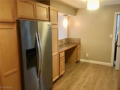 Kitchen featuring light brown cabinets, stainless steel fridge, light wood-type flooring, and pendant lighting | Image 3