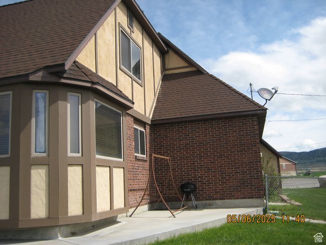 View of side of property with stucco siding, brick siding, a shingled roof, and fence | Image 4