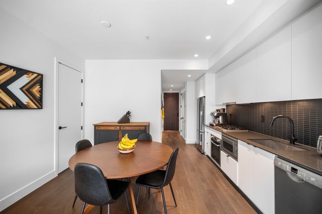 Kitchen with white cabinets, stainless steel appliances, dark wood-type flooring, modern cabinets, and decorative backsplash | Image 5