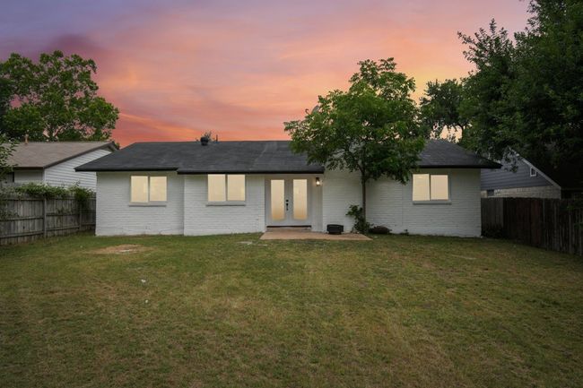 Back of property at dusk featuring french doors, a lawn, brick siding, and a fenced backyard | Image 22