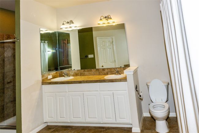 Bathroom with double vanity, a tile shower, and tile patterned flooring | Image 13