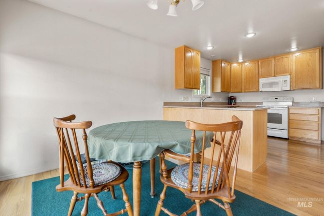 Kitchen featuring white appliances, light wood-type flooring, a peninsula, a kitchen breakfast bar, and recessed lighting | Image 8
