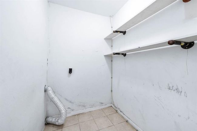 Laundry/Utility room inside off of the kitchen. It features a flexible duct and wall-mounted shelves, suitable for storage and appliances. | Image 13