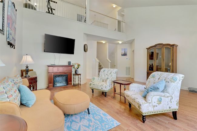 Living area with stairway, wood finished floors, a towering ceiling, and a glass covered fireplace | Image 5