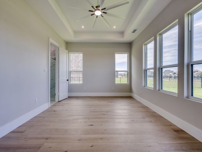 Primary bedroom featuring healthy amount of natural light, a raised ceiling, light wood-style floors, a ceiling fan, and recessed lighting | Image 31