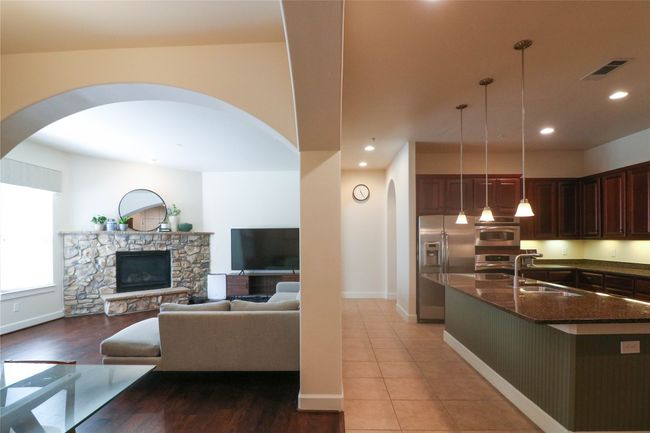 Kitchen featuring dark stone countertops, visible vents, arched walkways, a sink, and stainless steel appliances | Image 9
