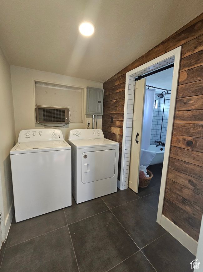Laundry area featuring washing machine and clothes dryer, dark tile patterned flooring, wood walls, and electric panel | Image 20