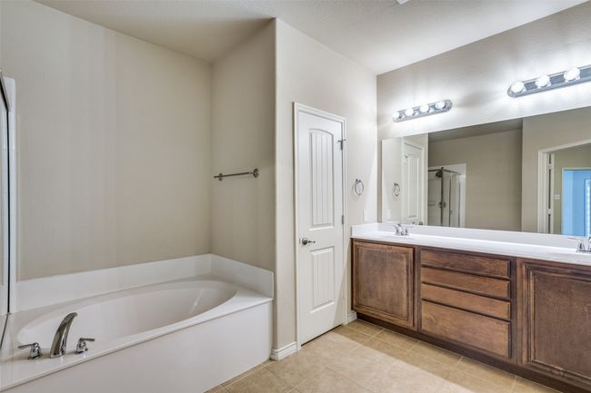 Full bathroom featuring tile flooring, a shower with door, double vanity, a sink, and a garden bathtub | Image 18