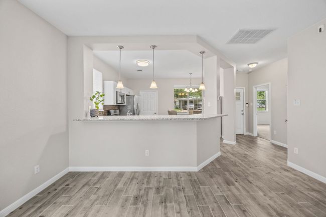 Kitchen with light wood finished floors, visible vents, appliances with stainless steel finishes, and white cabinetry | Image 12