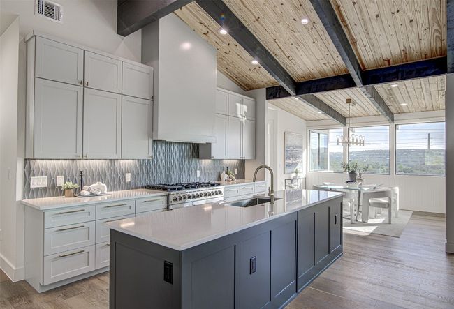 Kitchen featuring a sink, tasteful backsplash, light countertops, light wood-style flooring, and wood ceiling | Image 4