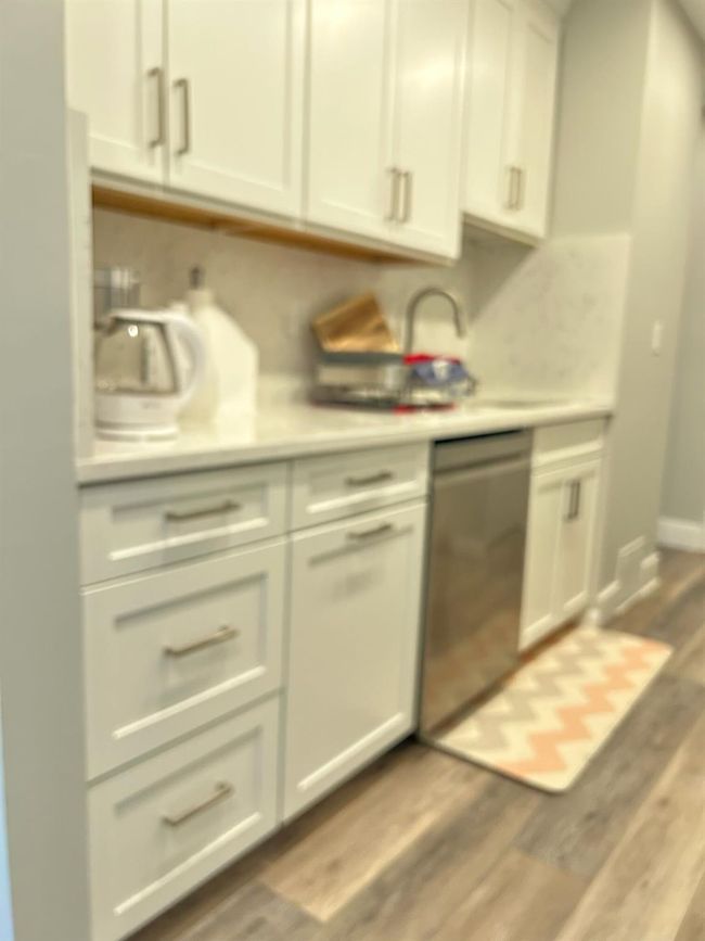 Kitchen with dishwasher, light countertops, wood finished floors, and white cabinets | Image 6