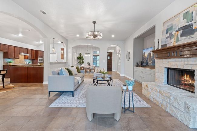 Living area featuring arched walkways, a chandelier, a fireplace, baseboards, and recessed lighting | Image 10