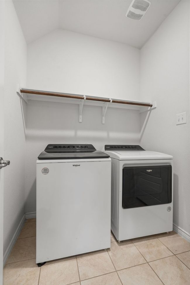 Laundry room with washing machine and clothes dryer, lighting, Shelf with clothes hanging rod, Tile floors, and Garage Entry | Image 22