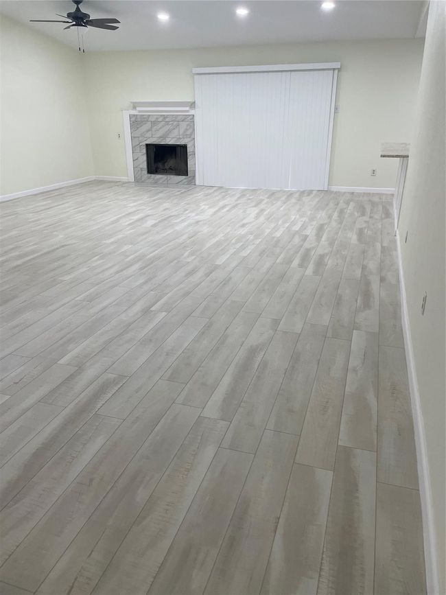Unfurnished living room with light wood-style flooring, a ceiling fan, baseboards, recessed lighting, and a premium fireplace | Image 25