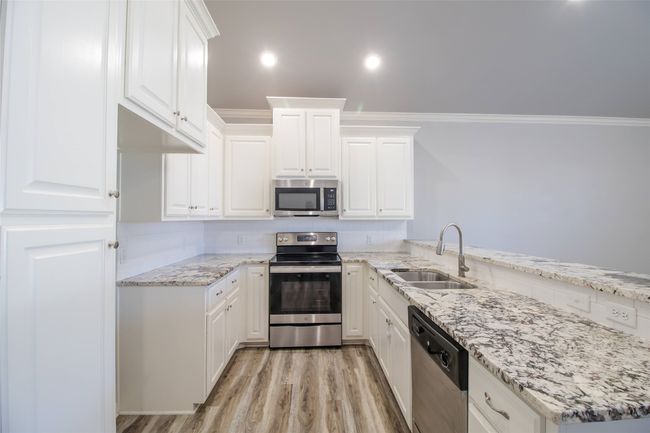 Kitchen with appliances with stainless steel finishes, ornamental molding, light stone countertops, white cabinetry, and recessed lighting | Image 4