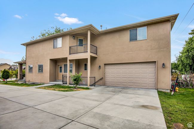 Townhome / multi-family property with a balcony, a garage, stucco siding, and driveway | Image 27