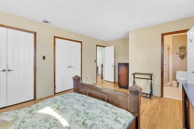 Bedroom featuring multiple closets, connected bathroom, visible vents, and light wood-style floors | Image 14